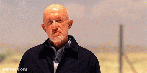 A Bald Man With A Beard Is Standing In The Middle Of A Field . GIF
