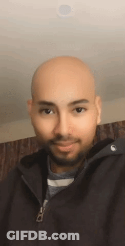 A Bald Man With A Beard Is Wearing A Black Jacket And Smiling For The Camera . GIF