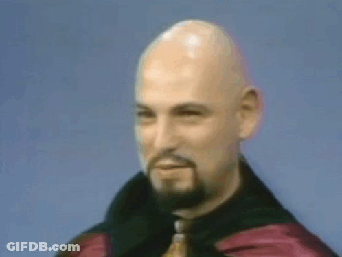 A Bald Man With A Beard Is Wearing A Black Jacket And Tie GIF
