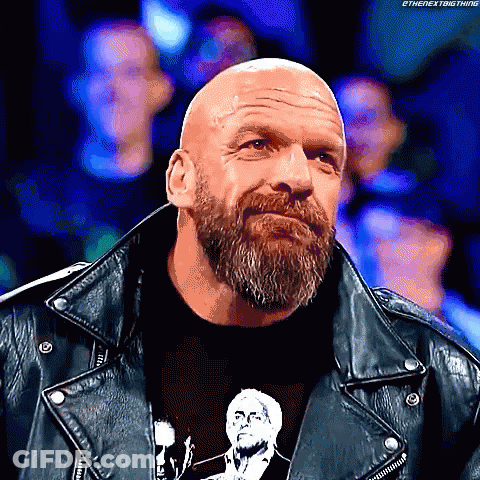 A Bald Man With A Beard Is Wearing A Black Shirt And A Leather Jacket GIF