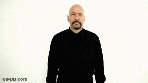 A Bald Man With A Beard Is Wearing A Black Shirt And Making A Hand Gesture GIF