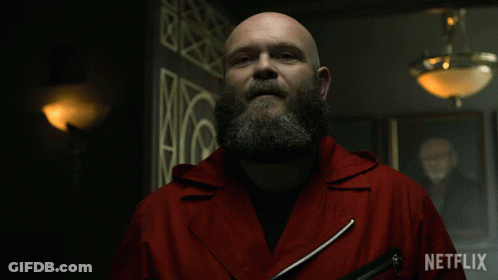 A Bald Man With A Beard Is Wearing A Red Jacket That Says Netflix On It GIF