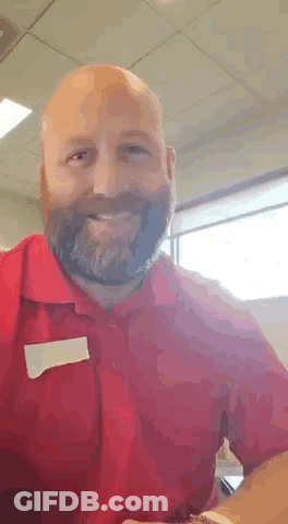 A Bald Man With A Beard Is Wearing A Red Shirt . GIF