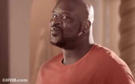 A Bald Man With A Beard Is Wearing A Red T-Shirt And Looking At The Camera . GIF