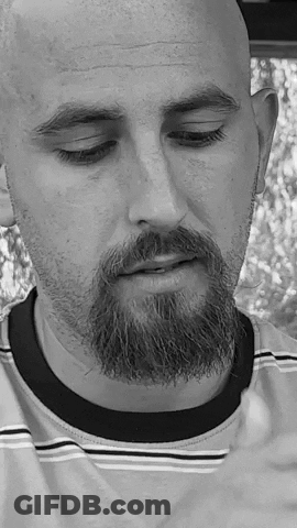 A Bald Man With A Beard Is Wearing A Striped Shirt And Has His Eyes Closed . GIF