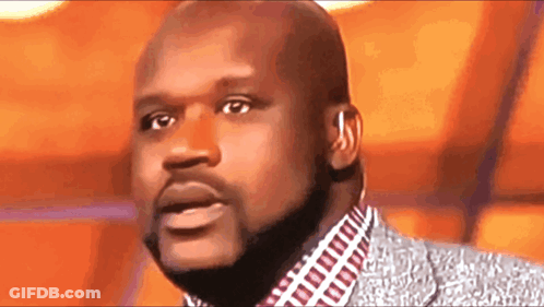 A Bald Man With A Beard Is Wearing A Suit And Ear Buds GIF
