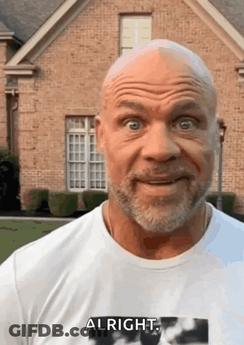 A Bald Man With A Beard Is Wearing A White Shirt That Says Alright GIF