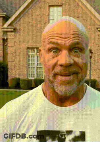 A Bald Man With A Beard Is Wearing A White Shirt With A Picture Of A Man On It In Front Of A Brick House GIF