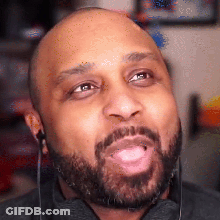 A Bald Man With A Beard Is Wearing Earbuds And Making A Funny Face . GIF