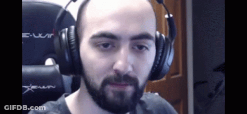 A Bald Man With A Beard Is Wearing Headphones And Making A Funny Face . GIF