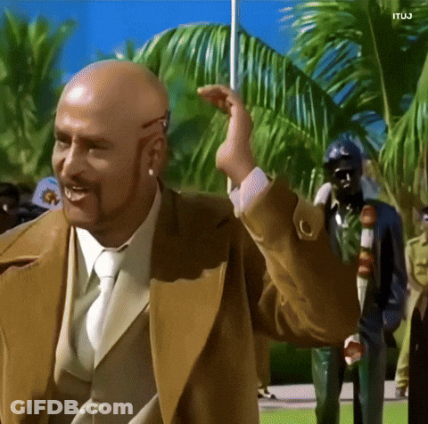 A Bald Man With A Beard Wearing A Tan Suit And Tie GIF