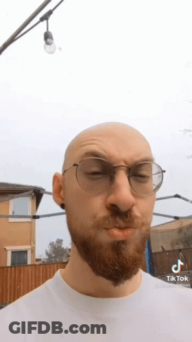 A Bald Man With A Beard Wearing Glasses And A White Shirt . GIF