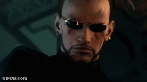 A Bald Man With A Beard Wearing Sunglasses Looks At The Camera GIF