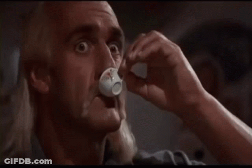 A Bald Man With A Mustache Is Drinking From A Small White Cup . GIF