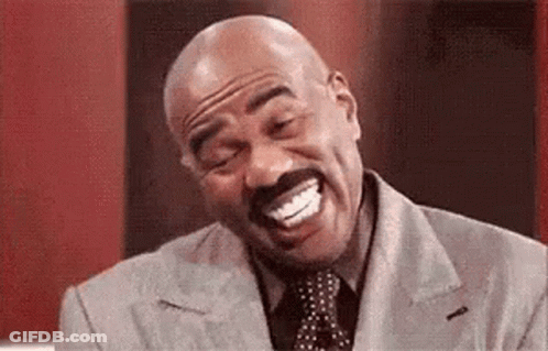A Bald Man With A Mustache Is Laughing With His Mouth Open While Wearing A Suit And Tie . GIF