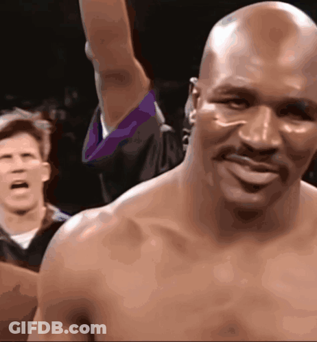 A Bald Man With A Mustache Is Smiling While A Referee Looks On GIF
