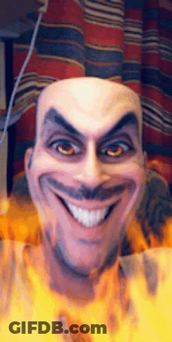 A Bald Man With A Mustache Is Smiling With Fire Behind Him GIF