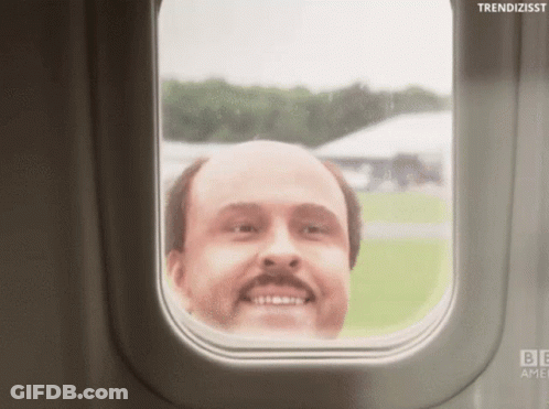 A Bald Man With A Mustache Looks Out A Window Of An Airplane GIF