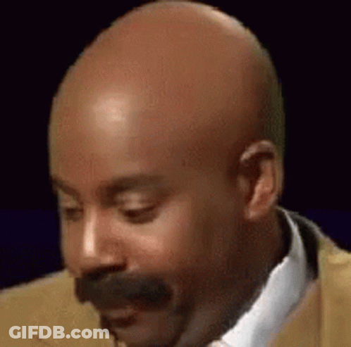 A Bald Man With A Mustache Wearing A Suit And Tie Is Making A Funny Face . GIF