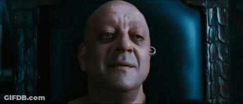 A Bald Man With A Piercing In His Ear Is Sitting In A Chair And Smiling . GIF