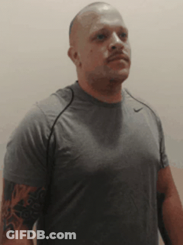 A Bald Man With A Tattoo On His Arm Is Wearing A Grey Nike Shirt GIF