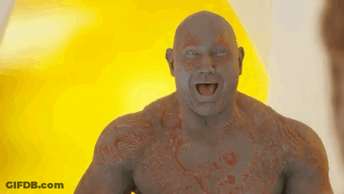 A Bald Man With A Tattoo On His Chest Is Standing In Front Of A Yellow Background . GIF