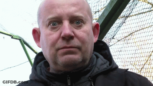 A Bald Man With Blue Eyes And A Beard Wears A Black Jacket GIF
