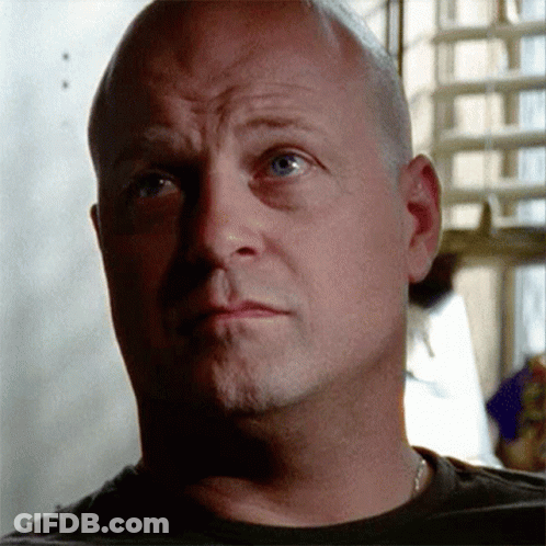 A Bald Man With Blue Eyes Looks At The Camera With A Serious Look On His Face GIF