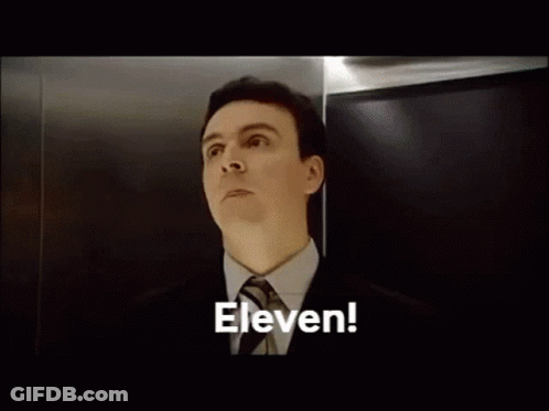 A Bald Man With Braces On His Teeth Is Looking Up At The Word Eleven GIF