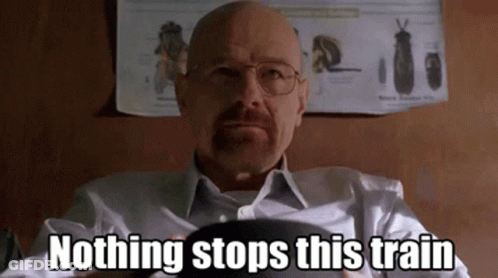 A Bald Man With Glasses And A Beard Is Sitting In Front Of A Poster That Says Nothing Stops This Train . GIF