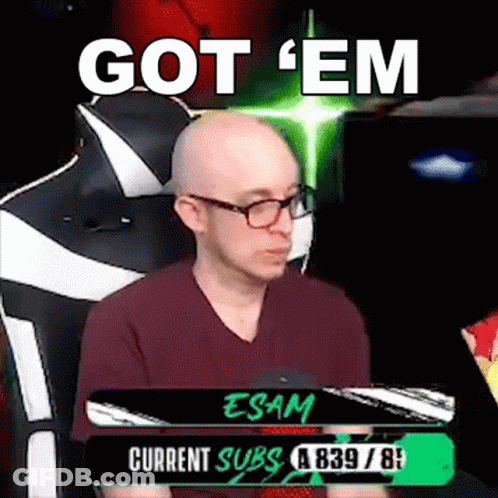 A Bald Man With Glasses Is Sitting In A Chair With The Words `` Got 'Em '' Written On The Screen . GIF
