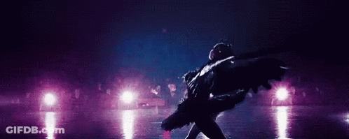 A Ballerina Is Dancing On A Stage In Front Of A Crowd In A Dark Room . GIF