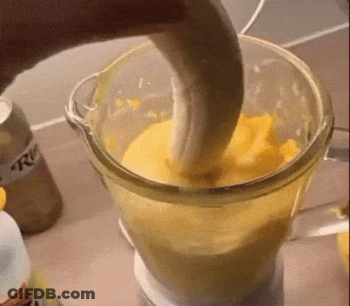A Banana Is Being Added To A Blender Filled With Yellow Liquid . GIF