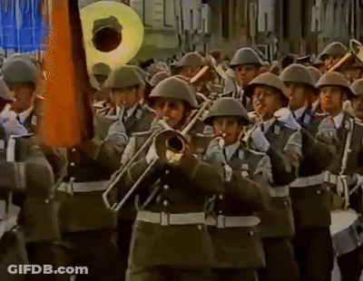 A Band Of Soldiers Marching In A Parade Playing Instruments Including A Trumpet GIF