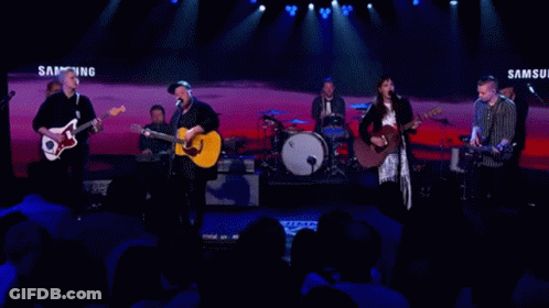 A Band Performs On Stage In Front Of A Samsung Banner GIF