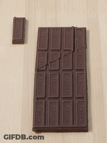 A Bar Of Hershey 'S Chocolate Is Broken In Half On A Table GIF
