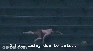 A Baseball Game Is Being Played In The Rain And The Scoreboard Says 2 Hour Delay Due To Rain GIF