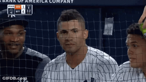 A Baseball Player Behind A Fence With A Scoreboard That Says Bank Of America Company On It GIF