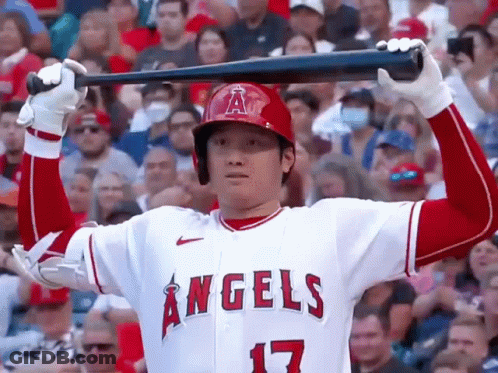 A Baseball Player For The Angels Is Holding A Bat Over His Head In A Crowded Stadium . GIF