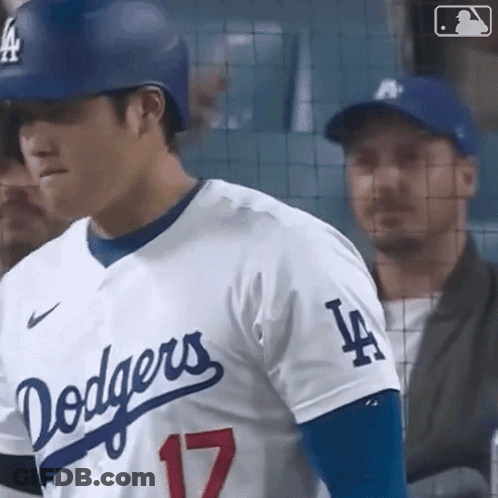 A Baseball Player For The Dodgers Is Standing In The Dugout Looking At The Camera . GIF