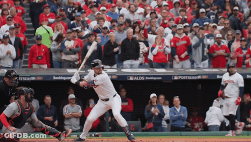 A Baseball Player Getting Ready To Hit A Ball In Front Of A Crowd With A Sign That Says Postseason On It GIF