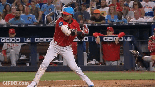 A Baseball Player Getting Ready To Swing At A Pitch With A Geico Banner Behind Him GIF