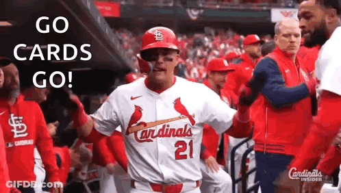 A Baseball Player In A Cardinals Uniform Is Standing In The Dugout With His Teammates . GIF