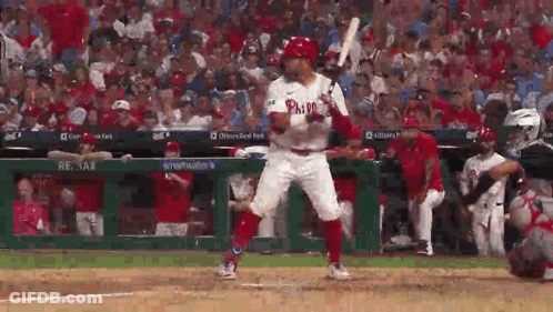 A Baseball Player In A Phillies Uniform Is Swinging A Bat At A Ball . GIF