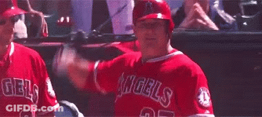 A Baseball Player In A Red Uniform Is Swinging A Bat At A Ball In A Dugout . GIF