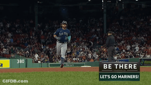 A Baseball Player In A Seattle Uniform Is Running Towards A Sign That Says Be There Let 'S Go Mariners GIF