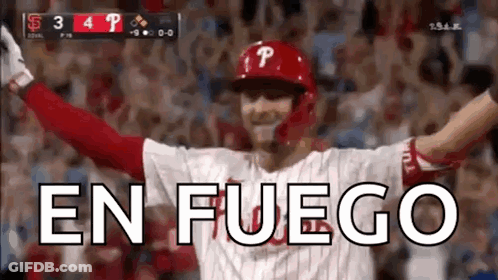 A Baseball Player Is Celebrating With His Arms In The Air And The Word En Fuego Is Visible In The Background . GIF