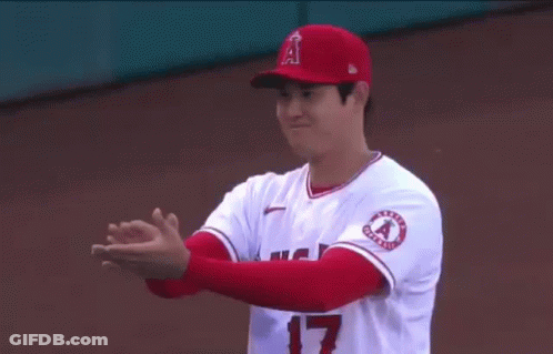A Baseball Player Is Clapping His Hands While Wearing A Red Hat And White Jersey . GIF