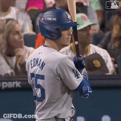 A Baseball Player Is Holding A Bat And Wearing A Helmet With The Letter L On It . GIF