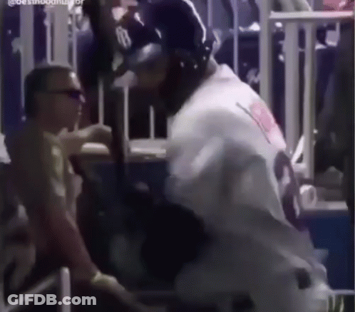 A Baseball Player Is Holding A Bat In A Stadium While A Man Looks On . GIF
